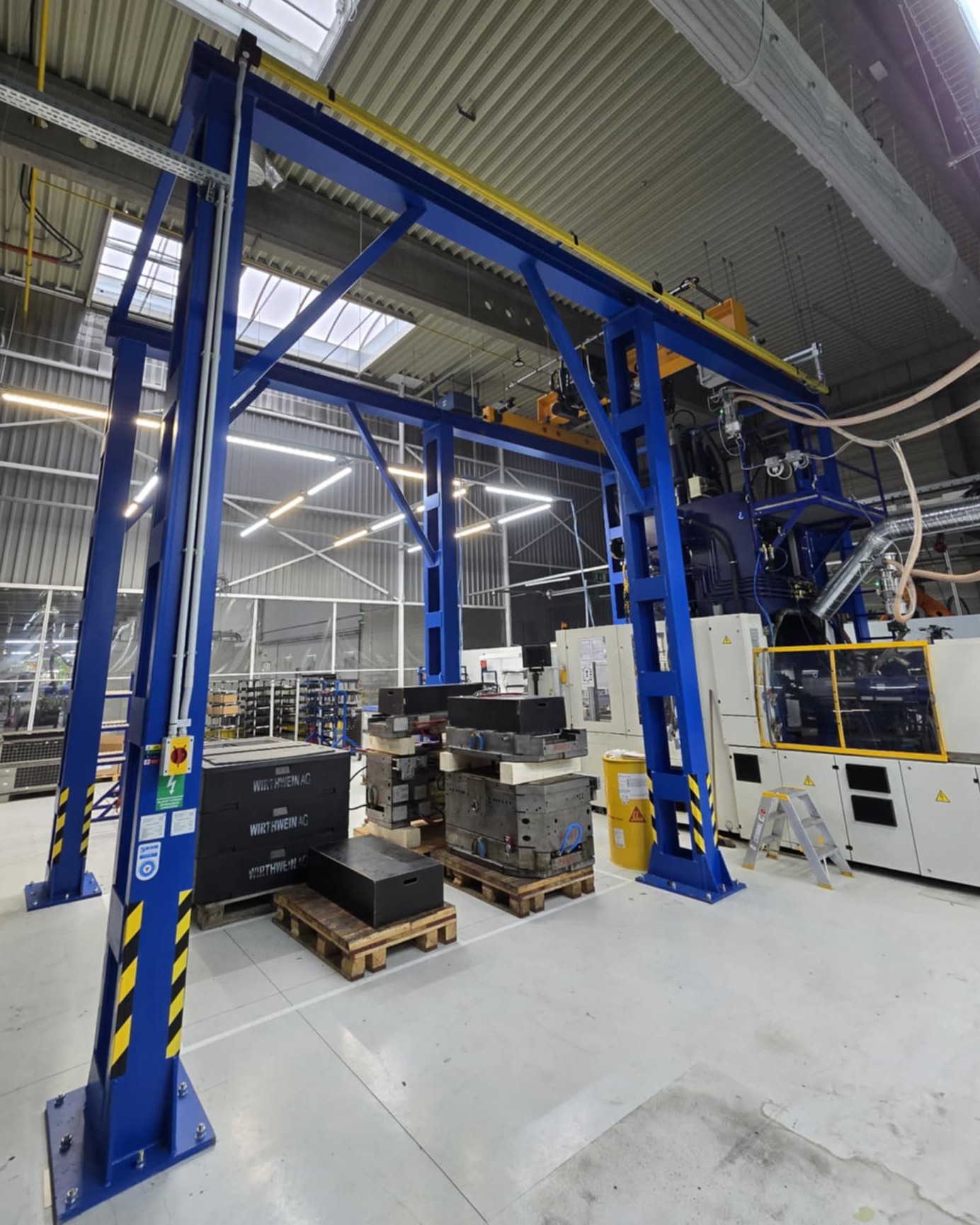 Mostový žeriav umiestnený vo výrobnej hale nad strojom